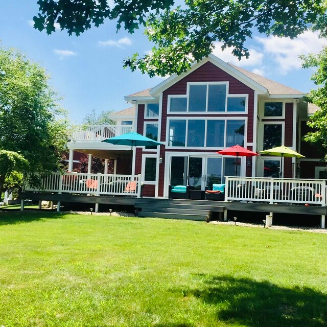 rear view of house featuring a wooden deck and a lawn