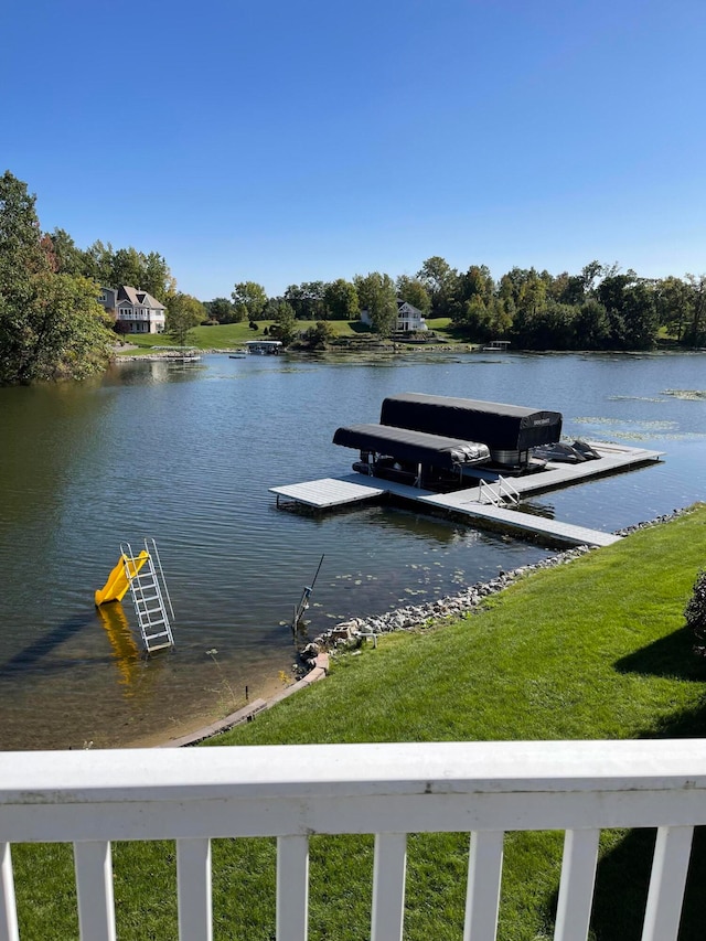 view of dock with a lawn and a water view