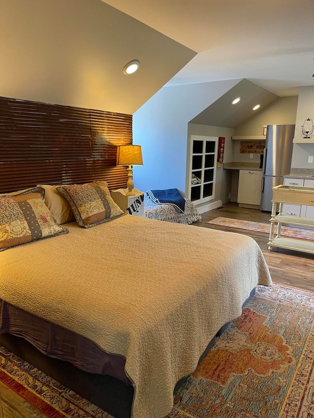 bedroom with lofted ceiling, hardwood / wood-style flooring, and stainless steel refrigerator