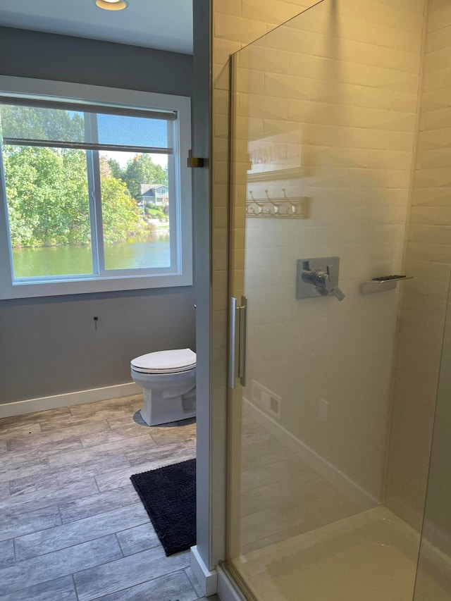 bathroom featuring walk in shower, hardwood / wood-style floors, and toilet