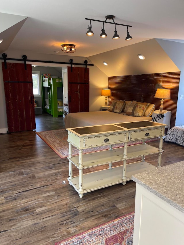 bedroom featuring vaulted ceiling, a barn door, and dark hardwood / wood-style flooring