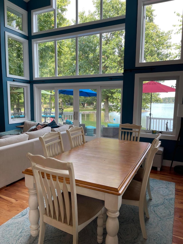 dining room featuring a water view, hardwood / wood-style flooring, and french doors