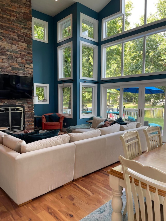 living room featuring wood-type flooring, a fireplace, and a towering ceiling