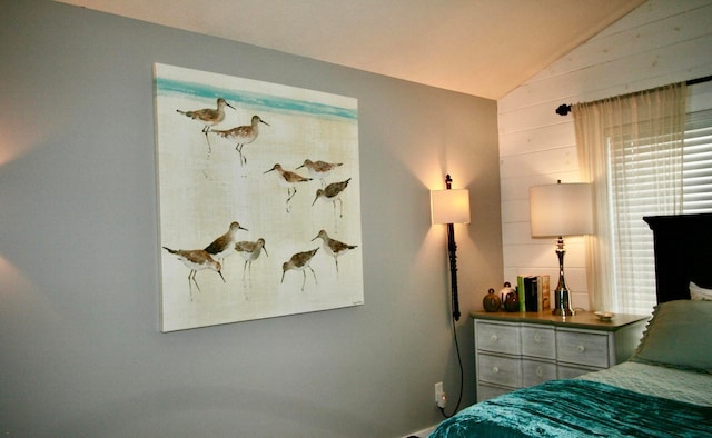 bedroom featuring wooden walls and vaulted ceiling