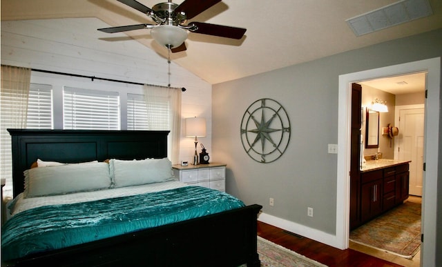 bedroom featuring vaulted ceiling, dark hardwood / wood-style flooring, ceiling fan, ensuite bathroom, and wooden walls