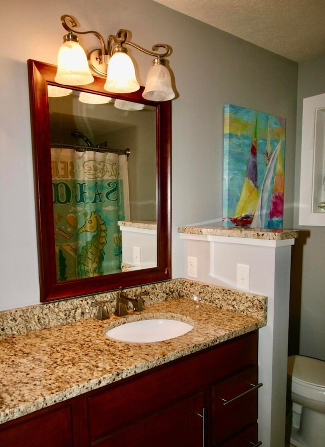 bathroom with vanity, toilet, a textured ceiling, and curtained shower