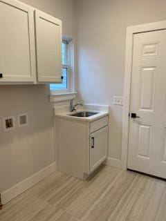 clothes washing area featuring hookup for a washing machine, cabinets, sink, and light wood-type flooring