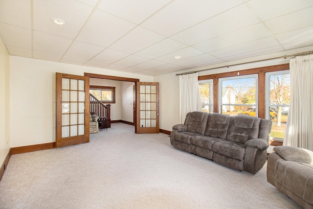 carpeted living room featuring french doors and a drop ceiling