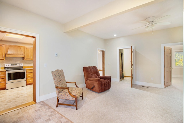 sitting room featuring light carpet, beamed ceiling, and ceiling fan