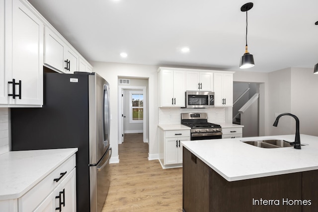 kitchen featuring hanging light fixtures, white cabinetry, sink, and stainless steel appliances