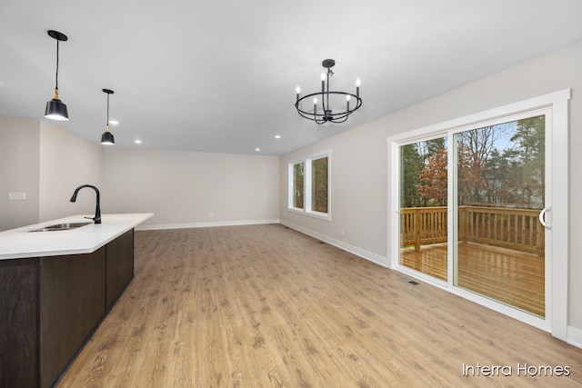 kitchen featuring decorative light fixtures, sink, a chandelier, and light hardwood / wood-style flooring