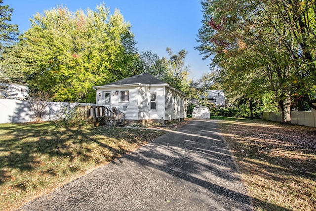 view of front of house featuring a storage unit and a front lawn