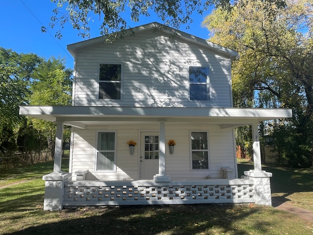 back of house featuring a lawn and covered porch