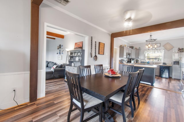 dining space with beam ceiling, crown molding, ceiling fan with notable chandelier, and dark hardwood / wood-style floors