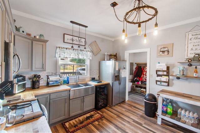 kitchen featuring pendant lighting, sink, appliances with stainless steel finishes, and hardwood / wood-style floors