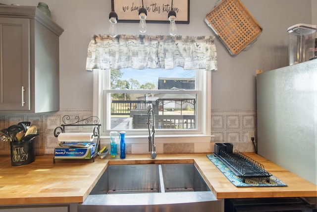 kitchen featuring gray cabinetry, sink, and wooden counters