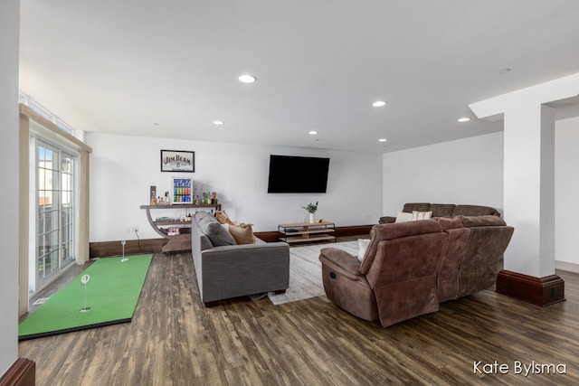 living room with dark wood-type flooring and golf simulator