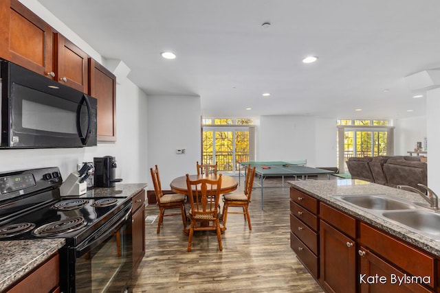 kitchen with dark stone countertops, sink, hardwood / wood-style floors, and black appliances