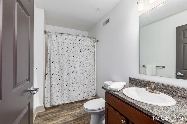 bathroom featuring hardwood / wood-style floors, vanity, walk in shower, and toilet