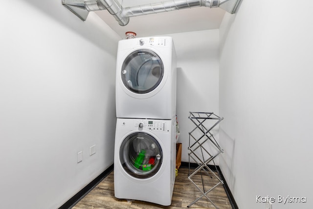 laundry area featuring stacked washer and clothes dryer and dark hardwood / wood-style floors