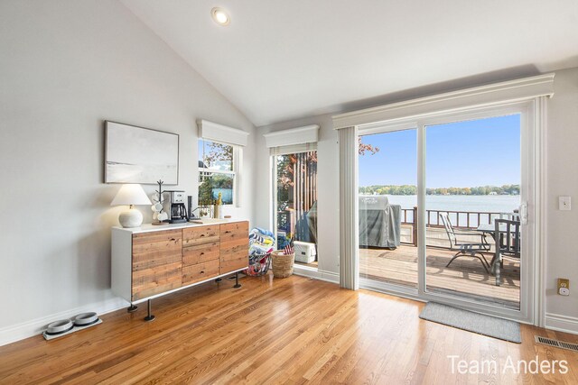 doorway to outside featuring a water view, light hardwood / wood-style floors, and lofted ceiling