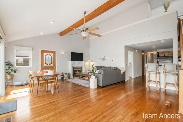 living room featuring beamed ceiling, light hardwood / wood-style flooring, and ceiling fan