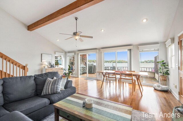 living room with light wood-type flooring, lofted ceiling with beams, a water view, and ceiling fan