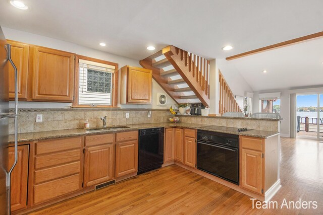 kitchen with black appliances, sink, light hardwood / wood-style flooring, vaulted ceiling, and kitchen peninsula