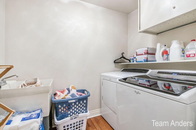 laundry area featuring washing machine and dryer, light hardwood / wood-style flooring, and cabinets