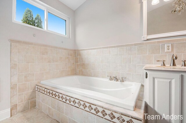 bathroom with tile patterned floors, tiled tub, lofted ceiling, vanity, and tile walls