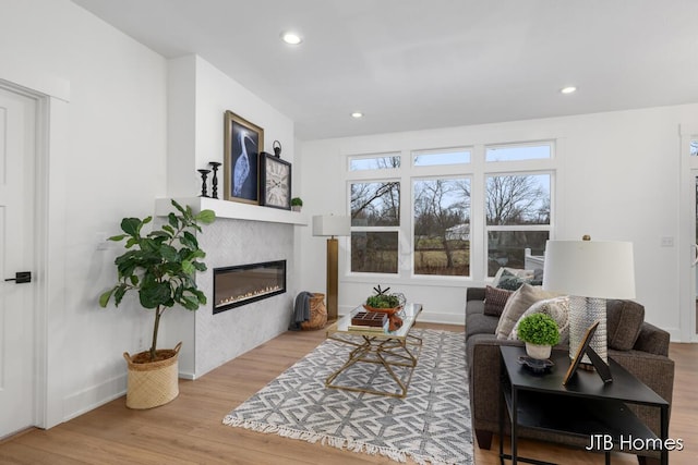 living room with a tile fireplace and light wood-type flooring