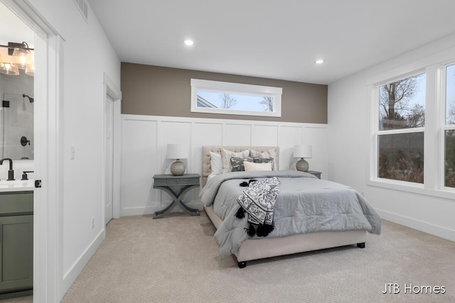 bedroom with ensuite bath, sink, and light colored carpet