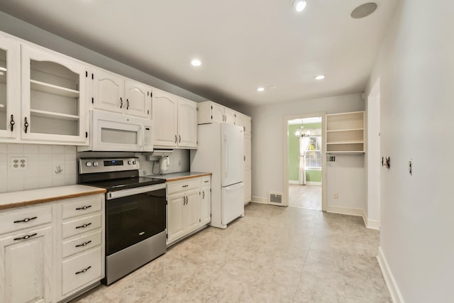 kitchen with tasteful backsplash, light tile patterned floors, an inviting chandelier, white cabinetry, and white appliances