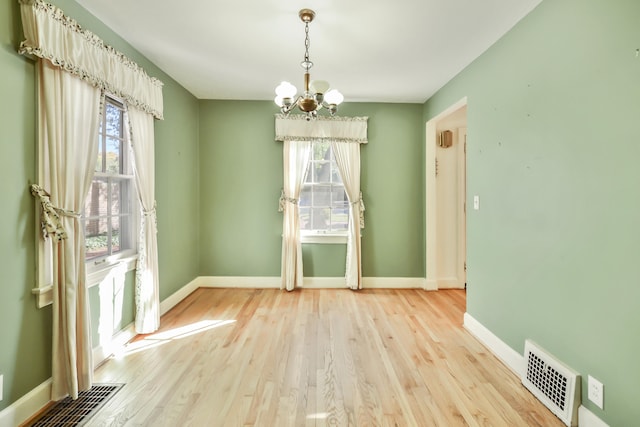 unfurnished dining area featuring light hardwood / wood-style flooring, a wealth of natural light, and a chandelier