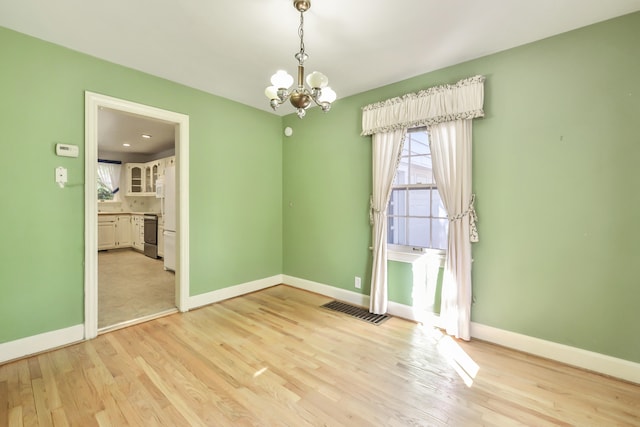 unfurnished room with a chandelier and light hardwood / wood-style flooring