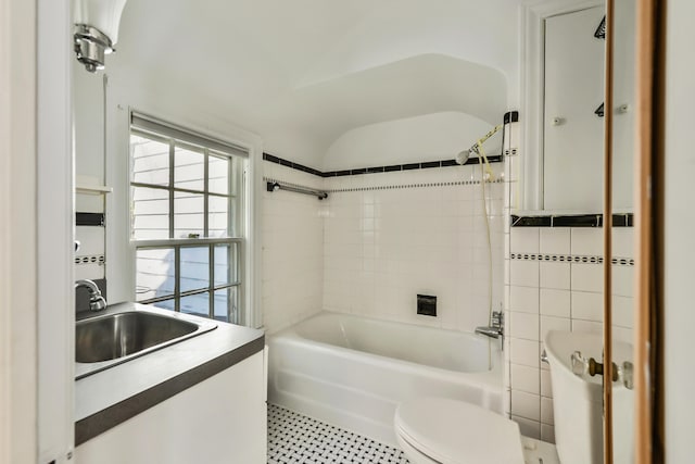 full bathroom featuring toilet, tiled shower / bath, vanity, and tile walls