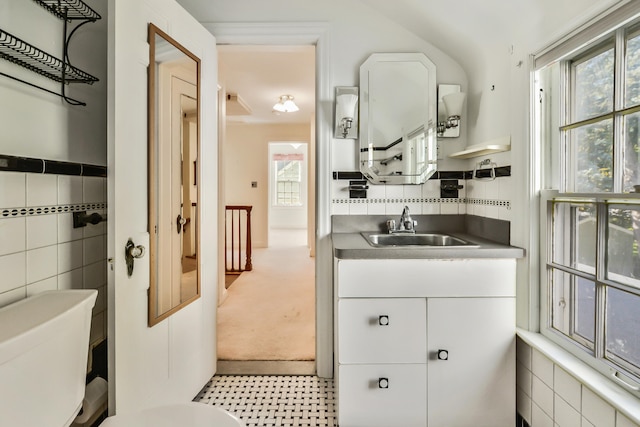 bathroom featuring toilet, vanity, and tile walls