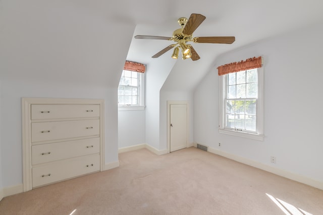 additional living space with ceiling fan, light colored carpet, and vaulted ceiling