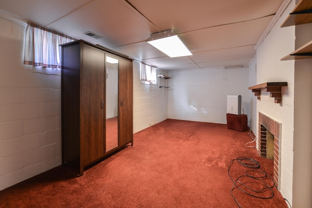 basement featuring a brick fireplace and dark carpet