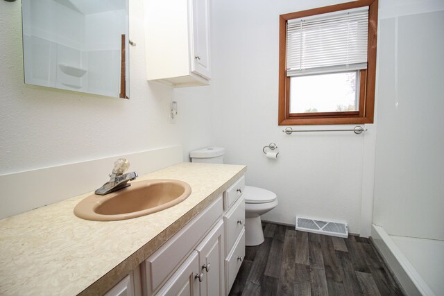 bathroom with visible vents, a shower, toilet, wood finished floors, and vanity