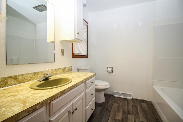 bathroom with toilet, vanity, wood finished floors, and visible vents