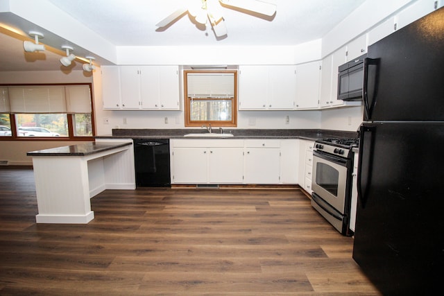 kitchen featuring dark countertops, black appliances, white cabinetry, and a sink