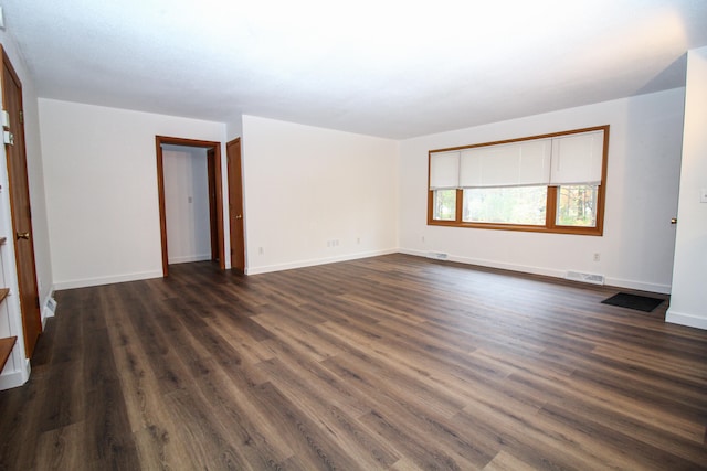 unfurnished room with dark wood finished floors, visible vents, and baseboards