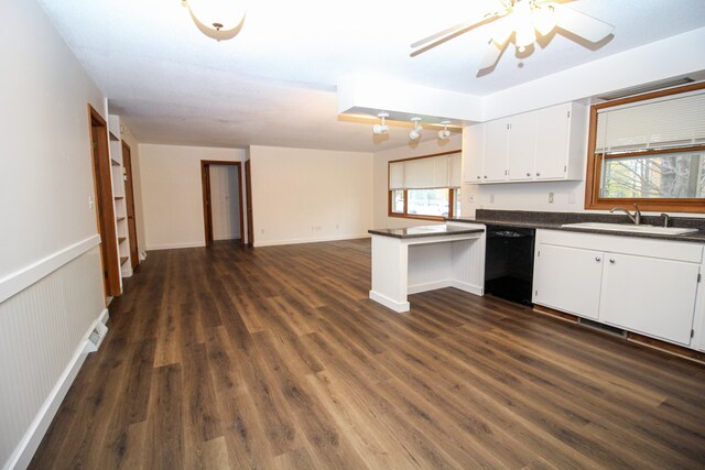 kitchen featuring dishwasher, dark countertops, open floor plan, white cabinetry, and a sink