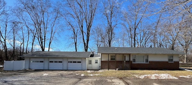 view of front facade with an attached garage, driveway, fence, and brick siding