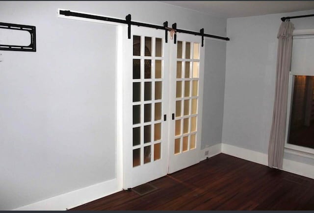 unfurnished room featuring dark hardwood / wood-style floors and a barn door