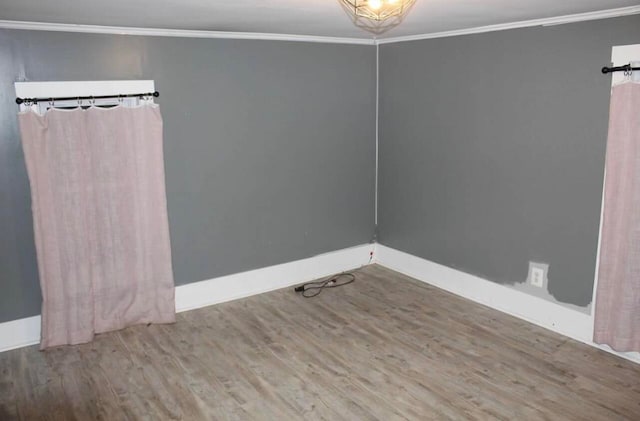 empty room featuring wood-type flooring and crown molding