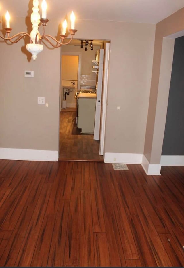 unfurnished room featuring dark hardwood / wood-style floors and an inviting chandelier