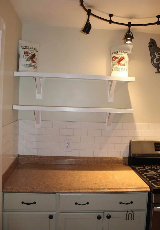 kitchen featuring gas stove, gray cabinetry, and backsplash