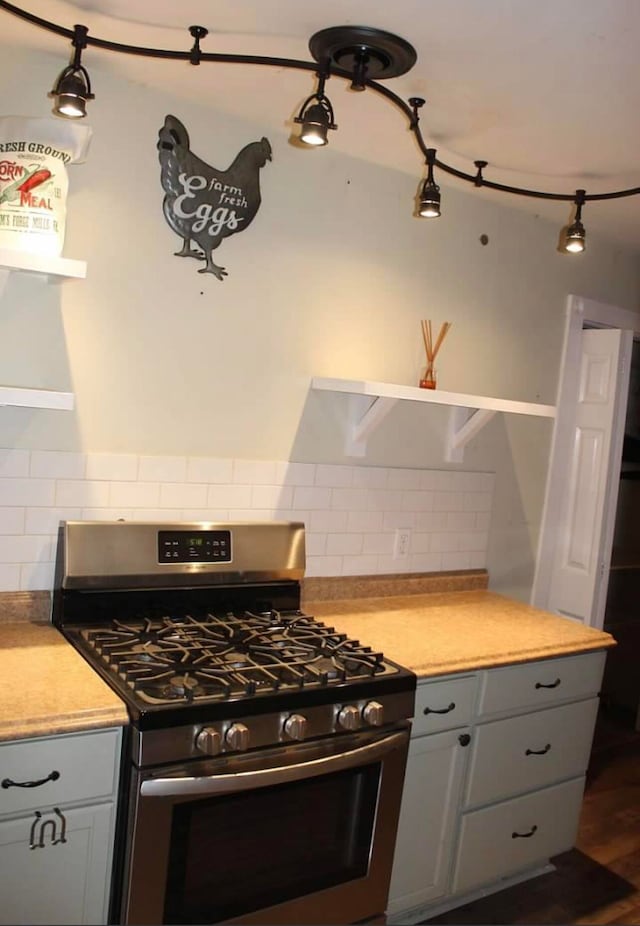 kitchen featuring gray cabinetry, dark hardwood / wood-style floors, stainless steel gas range oven, and backsplash